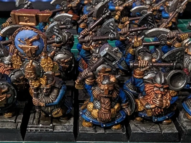 Ranked-up dwarf miniatures in blue and gold with axes over their shoulders, painted in an older studio style.