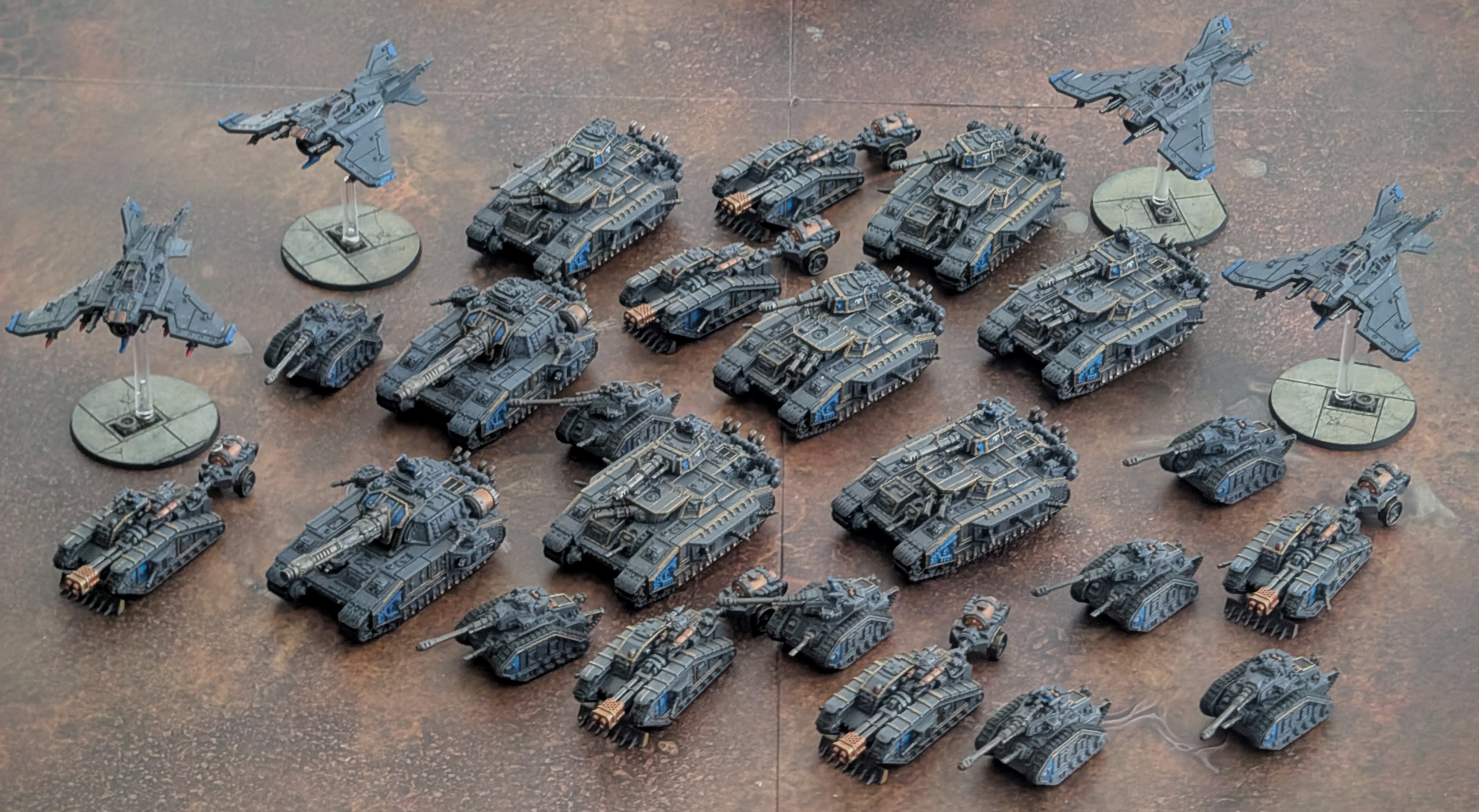 A finished Solar Auxilia force in grey and blue: five aircraft on flight stands surrounding rows of super-heavy tanks, Leman Russes, and transports.