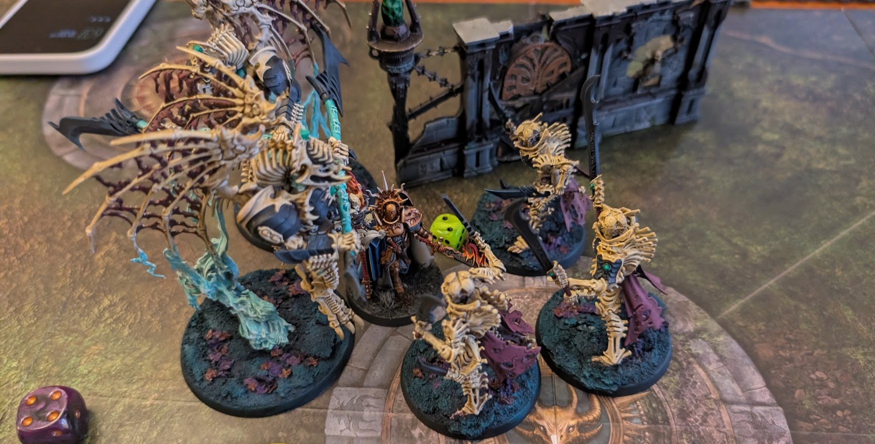 Painted Bonereaper miniatures on a gaming board: a winged skeletal construct and bone-armoured warriors closing in on a lone gold-armoured Stormcast hero.