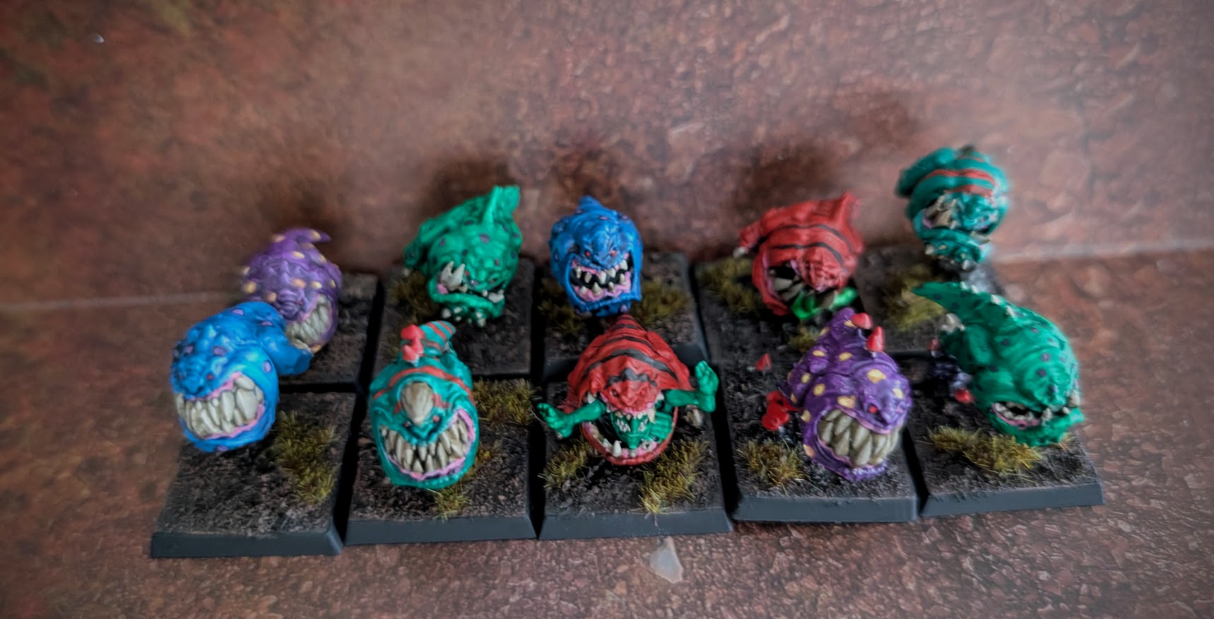 Ten brightly colored squig miniatures arranged in two rows.